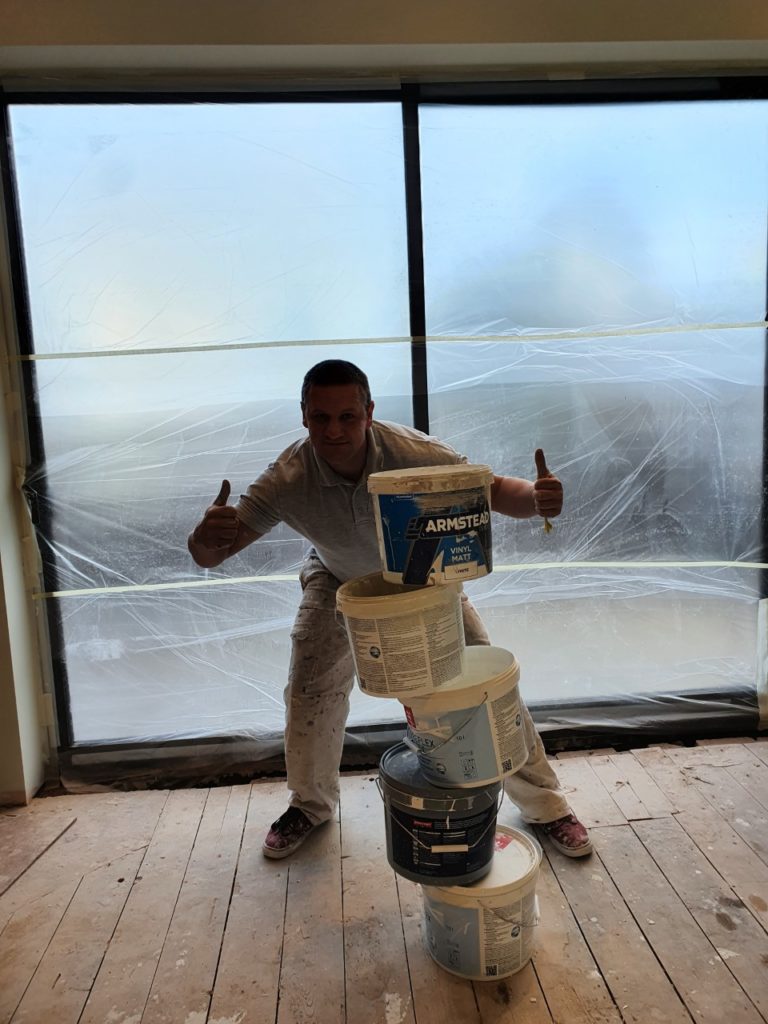 a decorator standing in fron of empty paint buckets
