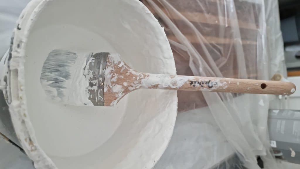 White Emulsion Paint in a kettle with a brush. Used for Painting Walls and Ceilings