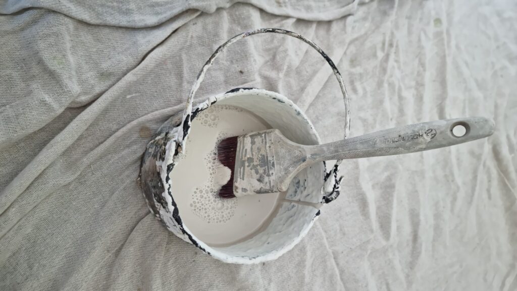 Vinyl matt paint in a kettle with a paint brush
