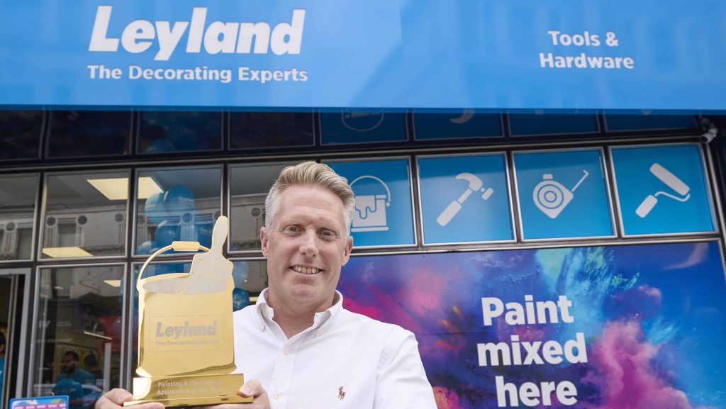 Man standing outside a Leyland Store in London